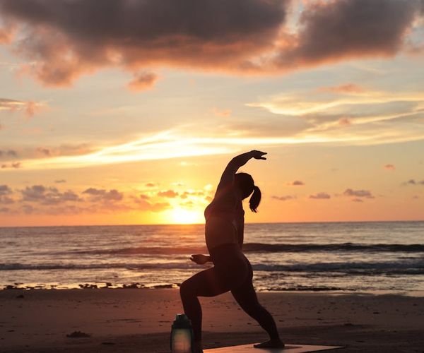 Silhouette of a person stretching during sunrise with warm tones.